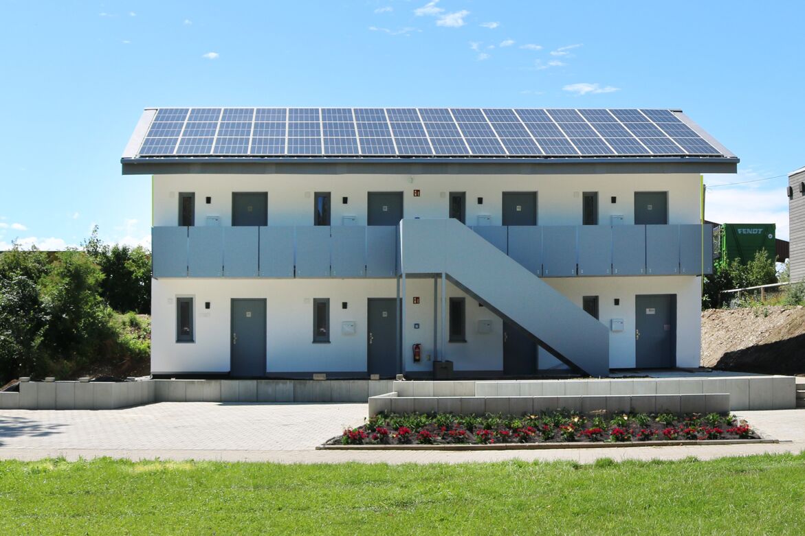 Modulare Unterkunft mit Solarpanelen Zweistöckige modulare Unterkunft mit Außentreppe und Solarpanelen auf dem Dach.
